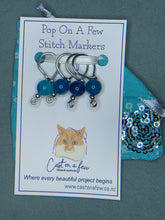 Load image into Gallery viewer, A set of four blue striped agate stone bead-equipped stitch markers with steel wire fixed markers, packaged in a recycled sari fabric drawstring pouch.